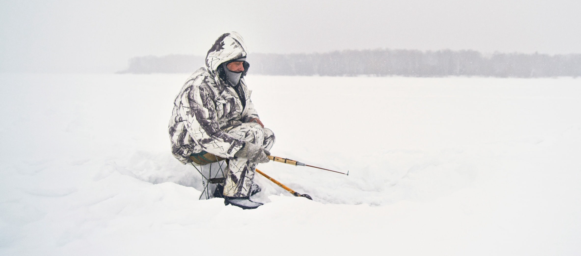 Homme qui attend sur la neige à la pêche