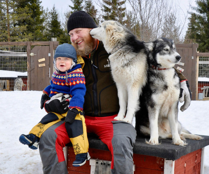 Lauri, organisateur de ballades en chiens de traineaux, pose ici avec son enfant et ses chiens.